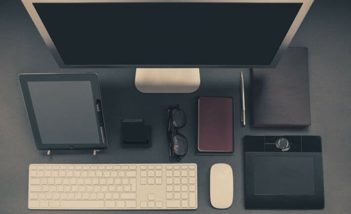 Schreibtisch, eine Tastatur, ein Monitor, ein Tablet, ein Smartphone, eine PC-Maus, ein GraphicTab, eine Brille